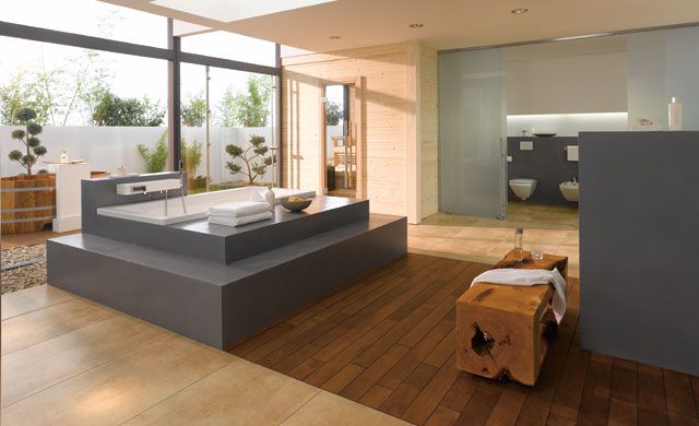 Modernes Badezimmer mit Fliesen in Holzoptik der Serie Bosco von Agrob Buchtal, freistehender Badewanne und Holzhocker.